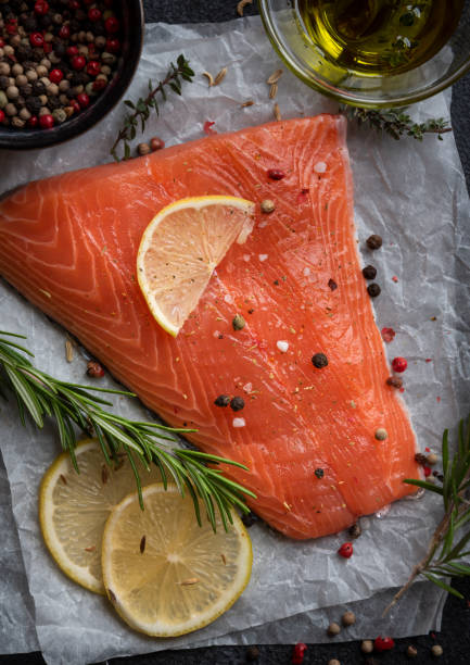 istock Uncooked raw salmon fish with herbs on dark background 1443499746