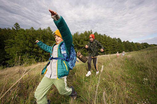 Brothers having fun and run outdoor near forest.