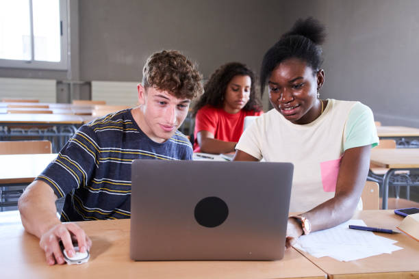 istock Young multiracial students using laptop while sitting on desk in the class together at college 1443502089
