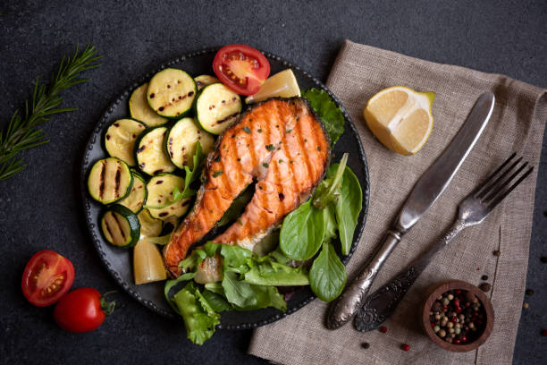 istock Cooked salmon fish with vegetables on dark background 1443502405