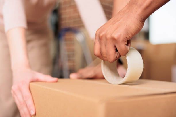 istock Husband and wife using adhesive scotch tape to pack up boxes 1443502423
