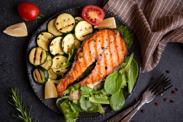 istock Cooked salmon fish with vegetables on dark background 1443502427