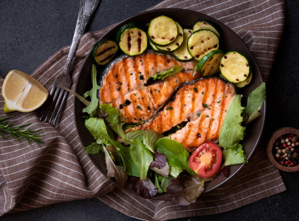 istock Cooked salmon fish with vegetables on dark background 1443502562