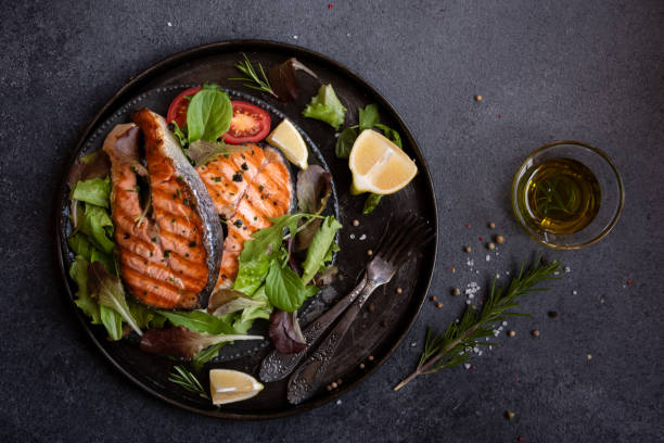 istock Cooked salmon fish with vegetables on dark background 1443502940