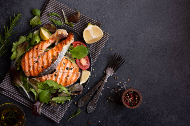 istock Cooked salmon fish with vegetables on dark background 1443503304