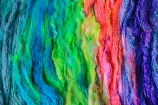 Bright and soft rainbow fibers are ready for spinning with the hand.