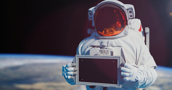 Spaceman holding a chroma key screen, standing against the Earth in an outer space