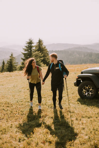 istock Smiling couple walking with backpacks over green hills 1443507414