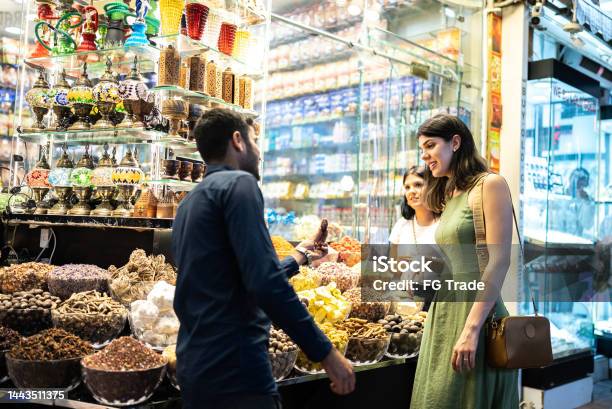 Salesman Talking And Selling Ingredients To Tourists In A Street Market Stock Photo - Download Image Now