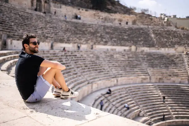 Mid adult man tourist admiring an ancient amphitheater in Amman, Jordan