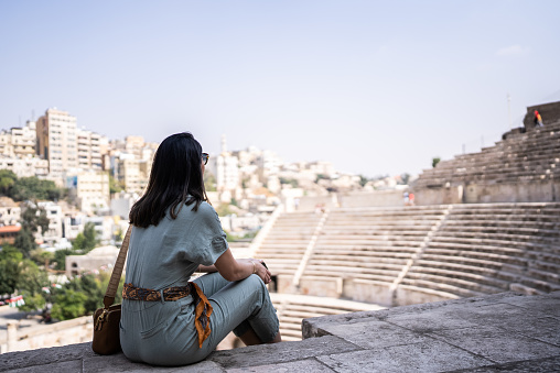 Mid adult woman tourist admiring an ancient amphitheater in Amman, Jordan