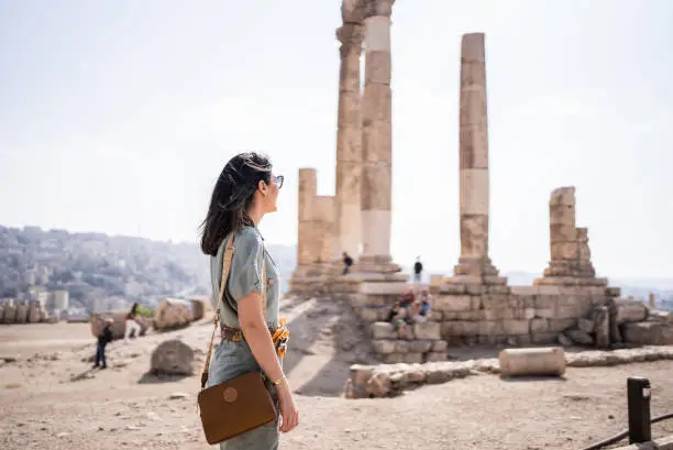 Mid adult woman tourist admiring antique columns in Amman city, Jordan