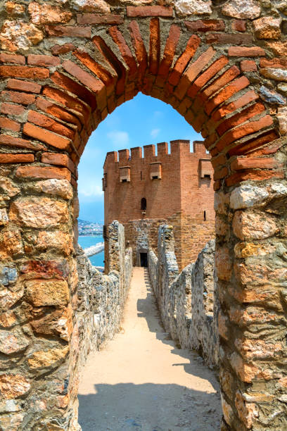 Top view at the Red Tower (Kizil Kule) as seen from the citadel wall. Tower is the symbol of Alanya, part of the medieval fortress. Antalya district, Turkey (Turkiye) Top view at the Red Tower (Kizil Kule) as seen from the citadel wall. Tower is the symbol of Alanya, part of the medieval fortress. Antalya district, Turkey (Turkiye) alanya stock pictures, royalty-free photos & images