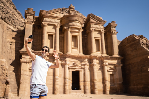 Mid adult man tourist taking a selfie or filming using mobile phone in Petra, Jordan
