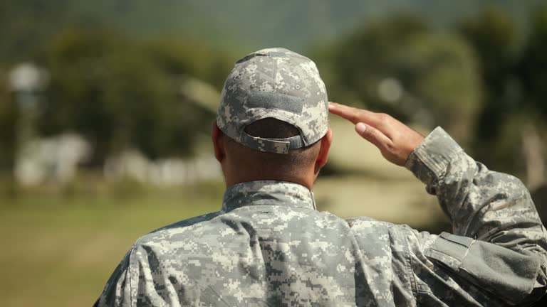 Soldier man in military uniform special forces saluting standing against on field Mission. Commander Army soldier military defender of  nation in uniform standing near battle tank while state of war.