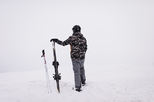 Young adult man on skiing on a foggy day. Copy space.