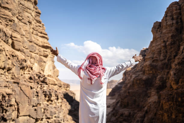 Rear view of a middle eastern man with arms open at desert