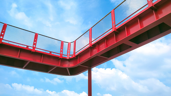 Low angle view of red metal skywalk against white clouds on blue sky background