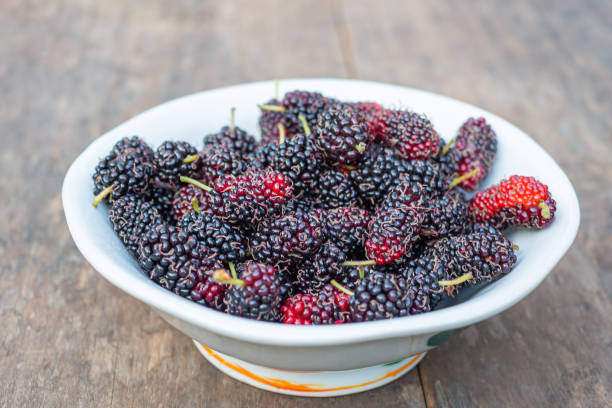 istock Ripe mulberries on white a dish on wooden table 1443517276
