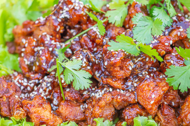 Close-up of fried chicken sprinkled with chili sauce, sesame, and scallion