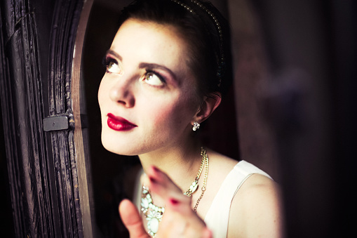 A young girl with short black hair in a dress poses in the studio with a disco ball. The concept of style and fashion. Girl on a shiny background. Holiday and fun concept. Selective focus, defocus.