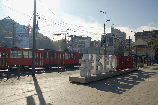 Belgrade, Serbia - 10/30/2022: Belgrade city street with a #belgrade sign on Slavia roundabout and tram on an autumn morning.