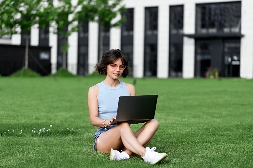 Beautiful smiling girl working with Macbook pro in the park