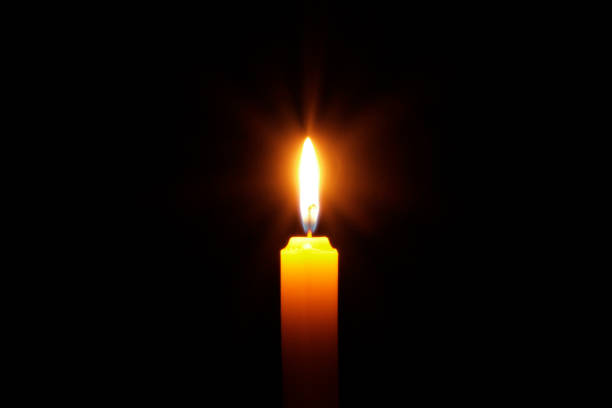 istock A candle with yellow light in the black background. Candle light illumination 1443518880