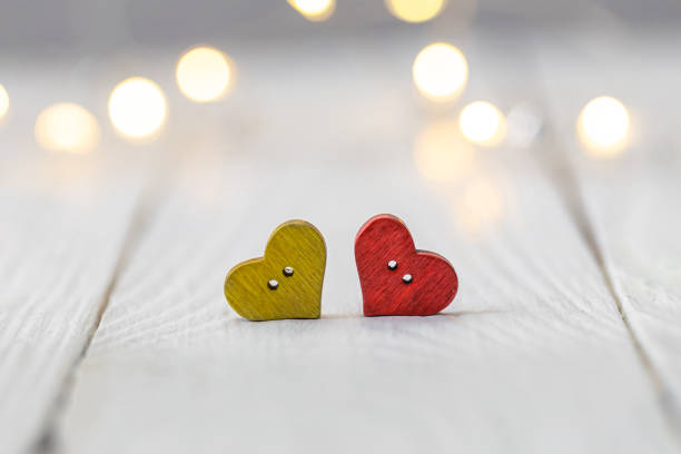 Small decorative hearts on a white wooden background with bokeh, macro shot, copy space.