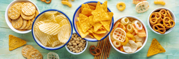 istock Salty snacks panorama. A table of assorted appetizers in bowls, overhead shot 1443519113