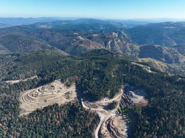 istock Industrial mine excavators are digging the soil in the construction site and loading trucks. Aerial drone top view. 1443519399