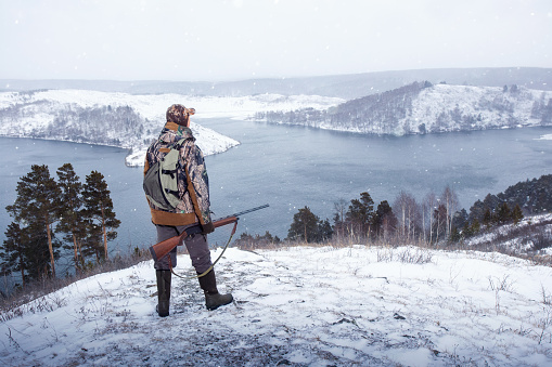 Hunter with rifle during a winter hunt. Male hobby, activity lifestyle concept.