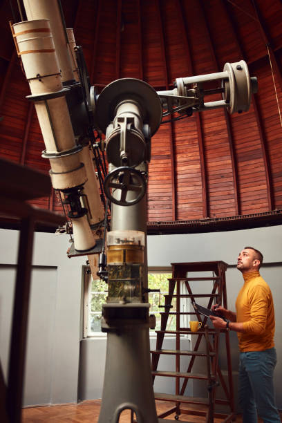 istock Astronomer with a big astronomical telescope in observatory doing science research. 1443520829