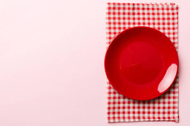 istock Top view on colored background empty round red plate on tablecloth for food. Empty dish on napkin with space for your design 1443520915