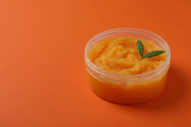 istock Cosmetic skin care scrub on orange background 1443522135