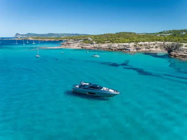 Motor boat is anchored up in beautiful turquoise waters in the summer in Ibiza