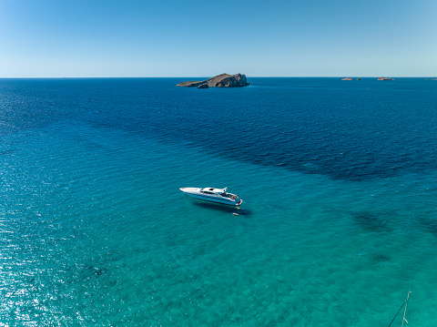 A luxury motor boat is anchored up in a beautiful bay in the summer.