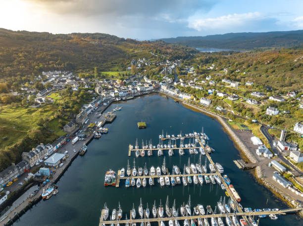 The Fishing Village of Tarbert in Scotland Aerial View Tarbet a small fishing village in Scotland sits on the shores of a loch and is a busy fishing port. The aerial view shows the waterfront, businesses and houses of this beautiful spot in Scotland loch fyne stock pictures, royalty-free photos & images