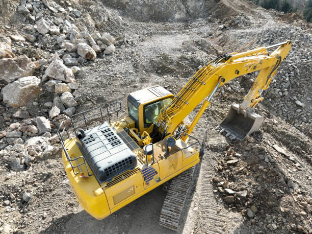 istock Industrial mine excavators are digging the soil in the construction site and loading trucks. Aerial drone top view. 1443525871