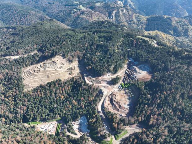 istock Industrial mine excavators are digging the soil in the construction site and loading trucks. Aerial drone top view. 1443525963