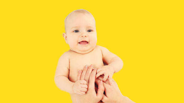 Portrait of mother massage her baby on yellow background stock photo