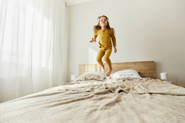 istock Carefree girl having fun while jumping on a bed. 1443529562