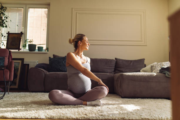 giovane donna incinta che fa yoga prenatale a casa - human pregnancy exercising relaxation exercise sport foto e immagini stock