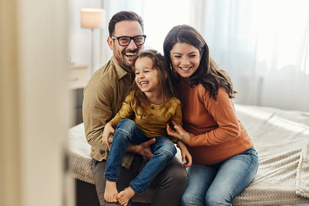 Young cheerful family having fun in bedroom. stock photo