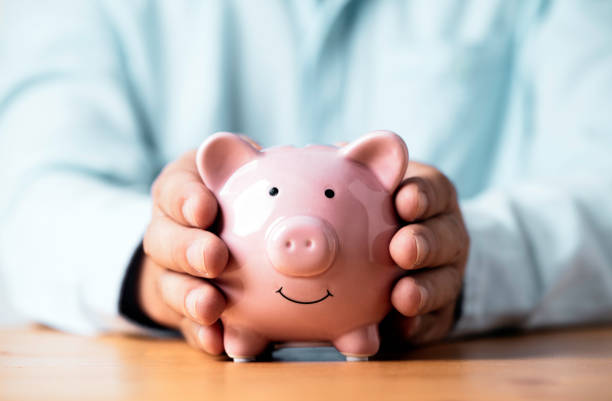 Businessman hand giving to pink piggy bank for deposit banking of investment , retirement to get profit and interest concept. Businessman hand giving to pink piggy bank for deposit banking of investment , retirement to get profit and interest concept. bank account stock pictures, royalty-free photos & images