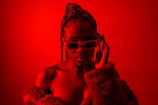 Attractive black ethnic woman with braids with red led lights, trap dancer with seductive look