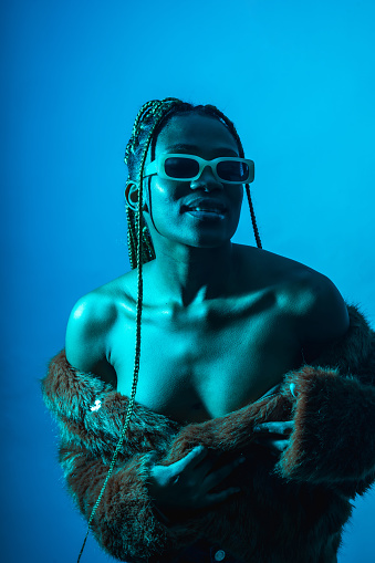 Attractive black ethnic woman with braids with blue led lights, trap dancer with seductive look