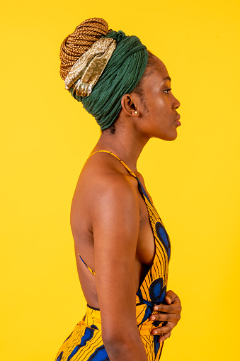 A person woman of black ethnicity with traditional costume on yellow background, profile model