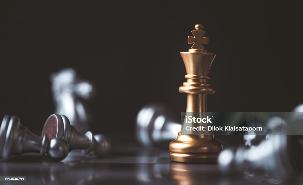 Golden king chess standing among fallen silver chess for winner and defeat after competition , Business strategy concept. Authority Stock Photo