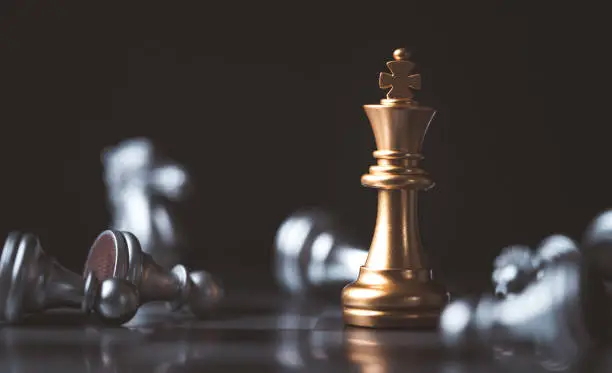 Photo of Golden king chess standing among fallen silver chess for winner and defeat after competition , Business strategy concept.